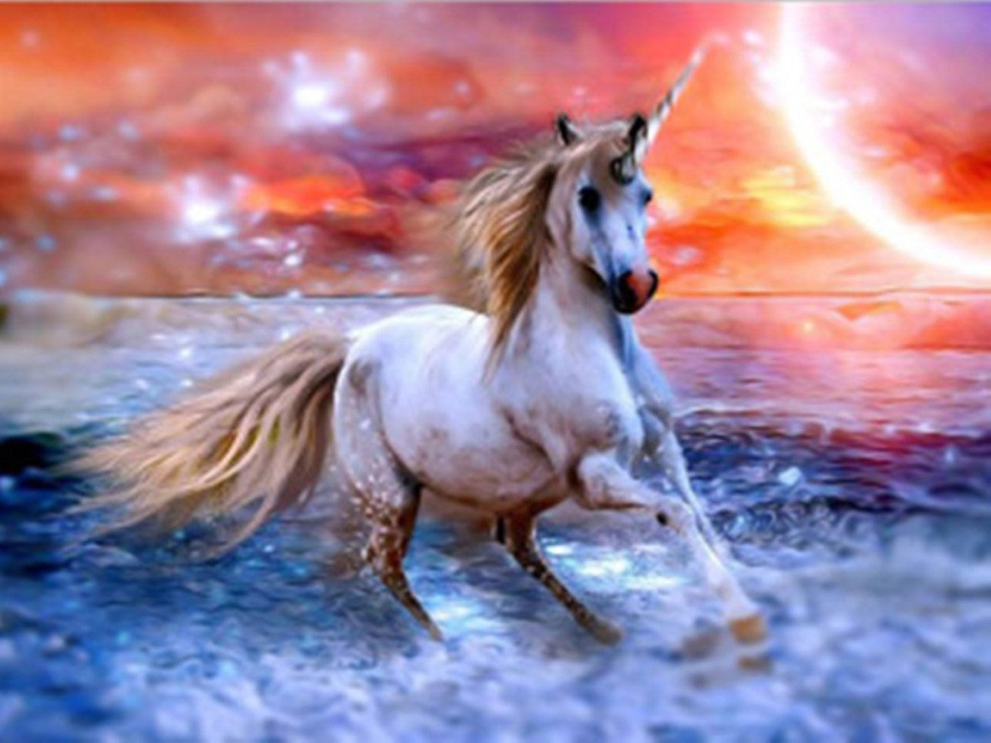 Diamond paint af enhjørning, der løber i vandkanten i solnedgangen. Orange himmel og blåt vand.