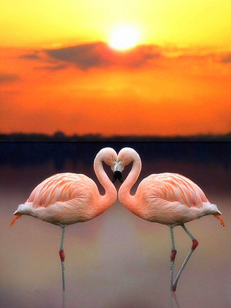 Diamond paint af to lyserøde flamingoer, der danner et hjerte i solnedgangens orange farver.