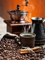 Diamond paint med dampende varm kaffekop med kværn og kaffebønner omkring. Orange baggrund.