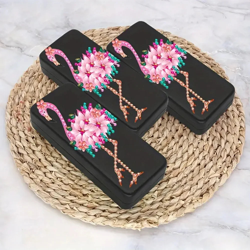 Etui til briller dekoreret med en farverig pink flamingo på sort baggrund. Sæt selv perlerne på.