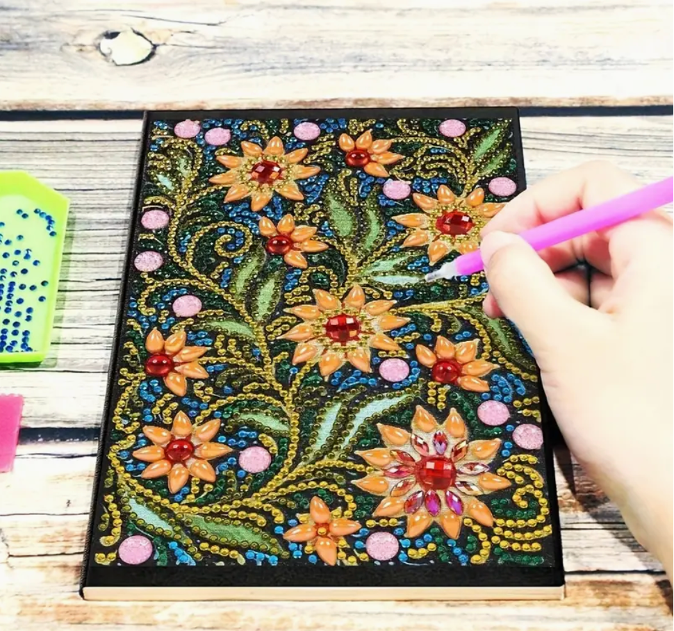 Notesbog dekoreret med diamanter. Motivet er gule og røde blomster.