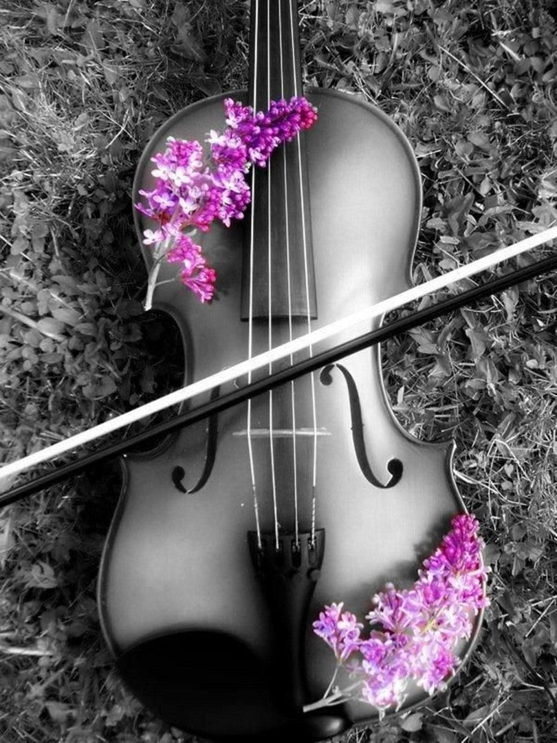 Diamond painting af en violin liggende på skovbunden. Sort/hvid med lilla syrener på.