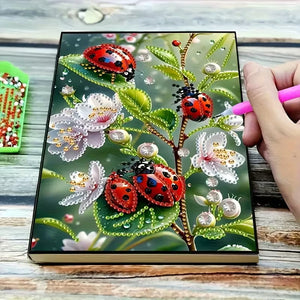 Diamond painting notesbog med mariehøns siddende på en blomstergren.