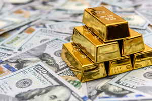 Diamond paint af dollarsedler spredt ud på et bord med 6 guldbarrer ovenpå.