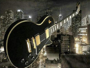 Diamond paint af sort guitar, der svæver i en skyline over storby om natten.