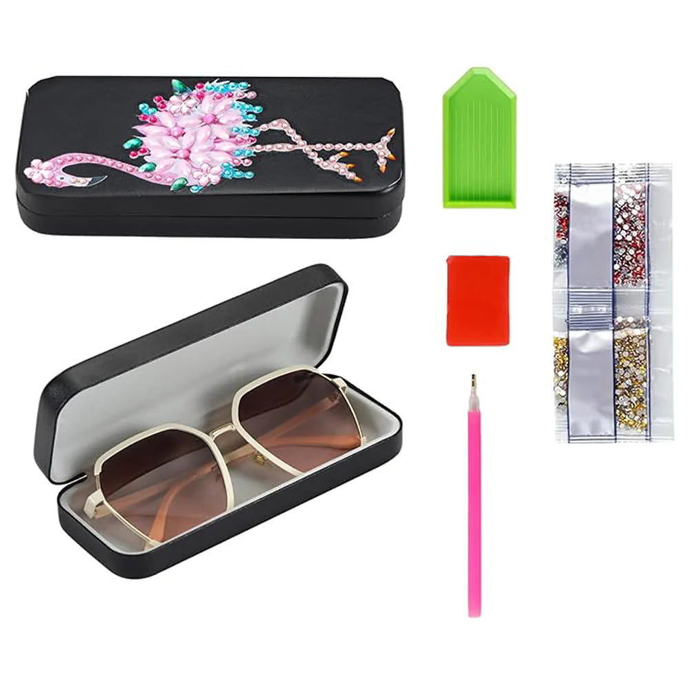 Etui til briller dekoreret med en farverig pink flamingo på sort baggrund. Indhold i kit vises.