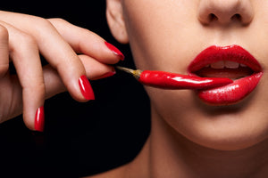 Erotisk diamond paint af kvinde med rød læbestift, der holder en rød chili op til læberne.