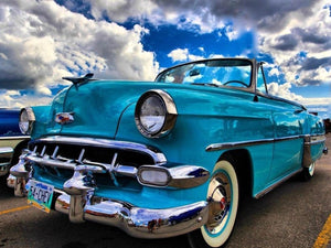 Diamond paint af en klassisk lyseblå cabriolet. Hvide skyer og blå himmel i baggrunden.