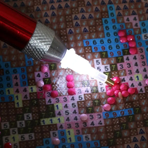 Rød pen til diamond painting. 
Der er lys i tippen, der lyser lærredet op.